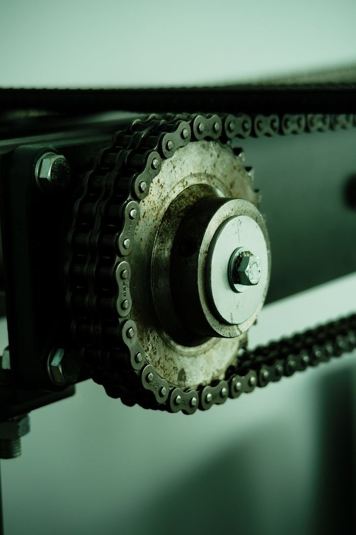 Detailed view of a rusty chain mechanism with a metal wheel, showcasing industrial engineering.