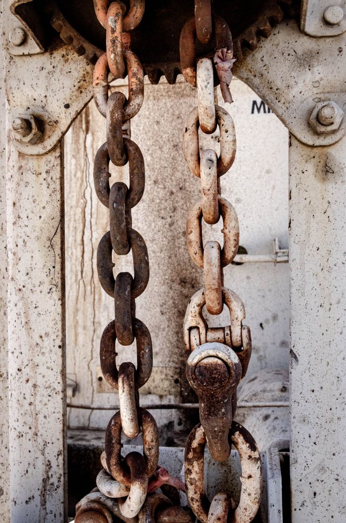 Shabby old metal chain lock with rusty details hanging on weathered construction in daytime