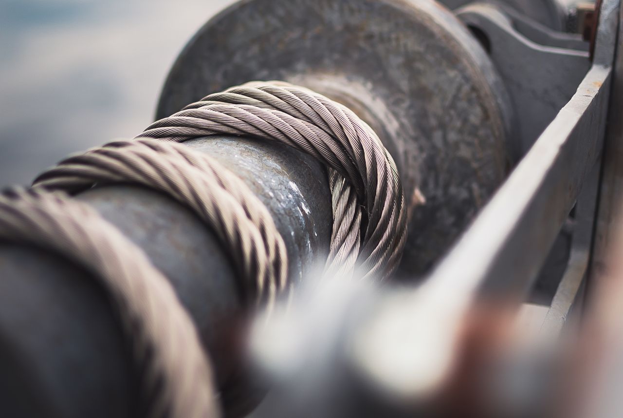 Detailed view of a strong steel cable wrapped around a mechanical reel, showcasing industrial strength.